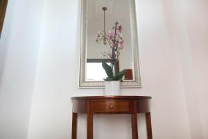 een vaas met bloemen op een tafel voor een spiegel bij Colombo Suites in Peschici