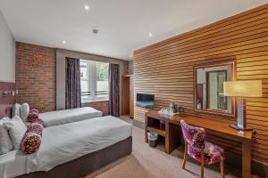 ein Hotelzimmer mit 2 Betten, einem Schreibtisch und einem TV in der Unterkunft The Rutland Hotel in Sheffield