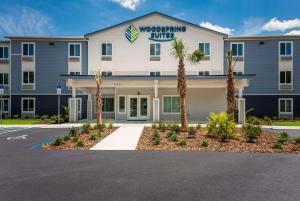 a hotel with palm trees in front of a building at WoodSpring Suites Inverness in Inverness