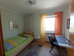 a bedroom with a bed and a desk and a window at Ferienwohnung Ingeborg 