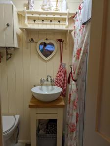 uma casa de banho com um lavatório e um espelho em forma de coração em Shepherds Hut with Hot Tub em Fryup