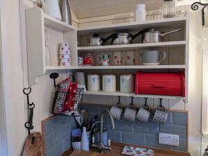 a kitchen with a shelf with cups and utensils at Shepherds Hut with Hot Tub in Fryup