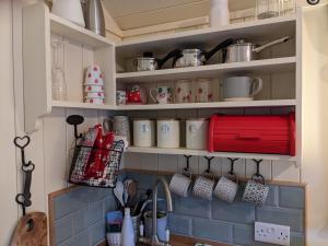 a kitchen with a shelf with cups and utensils at Shepherds Hut with Hot Tub in Fryup