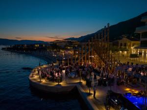 un grupo de personas de pie en un muelle de noche en Portonovi Resort en Herceg-Novi