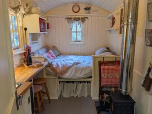 a small bedroom with a bed in a tiny house at Shepherds Hut with Hot Tub in Fryup