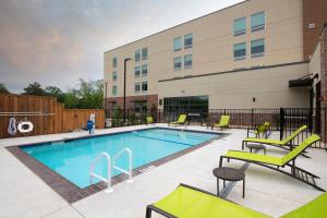a swimming pool with chairs and a building at SpringHill Suites by Marriott Lindale in Lindale