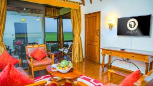 a living room with a television and a table and chairs at Paraa Safari Lodge in Paraa