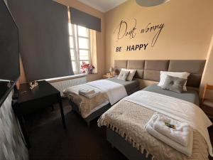 a bedroom with two beds and a sign that reads dirt mummy be happy at Apartamenty Azzurro in Kielce