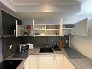 uma cozinha com armários brancos, um lavatório e um micro-ondas em Apartment Lilletveitvegen em Bergen