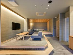 人吉市にあるHitoyoshi Onsen Nabeyaのソファとテレビ付きのホテルルーム