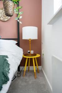 a yellow table with a lamp on it next to a bed at Stylish Cardiff City Apartment with Parking in Cardiff