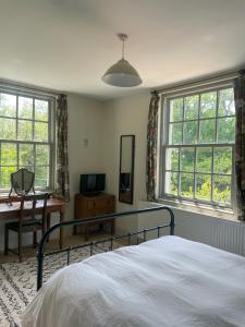 Un dormitorio con una cama, un escritorio y ventanas. en Starnash Farmhouse Holiday Home, en Hailsham