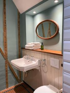 La salle de bains est pourvue d'un lavabo, d'un miroir et de toilettes. dans l'établissement Starnash Farmhouse Holiday Home, à Hailsham