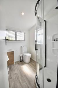 a white bathroom with a shower and a toilet at Premium Comfortable Lake View 2BR in Taupo