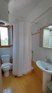 a bathroom with a toilet and a white shower curtain at AGNANTIO HOME in Monemvasia