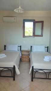two beds in a room with a window at AGNANTIO HOME in Monemvasia