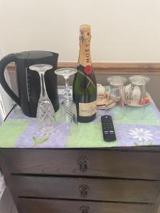 una botella de vino y copas en un tocador en Les Fleurs Accommodation en Dover