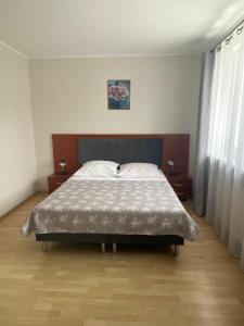 a bedroom with a bed and two night stands and two windows at Apartamenty Rodzinne Zdrojowe in Kudowa-Zdrój