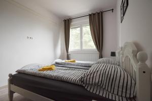 a bedroom with a bed with striped sheets and a window at Piccoleto Bianco in Badacsonytomaj