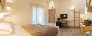 a bedroom with a bed and a desk and a television at Hôtel Palombaggia in Porto-Vecchio