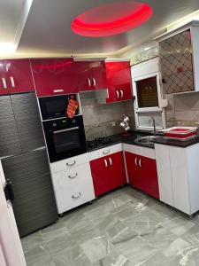 una cocina con armarios y electrodomésticos rojos y blancos en Eden Park, in Algeria by the beach. en Orán
