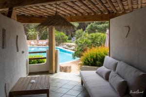 a living room with a couch and a table and a pool at Hôtel Palombaggia in Porto-Vecchio