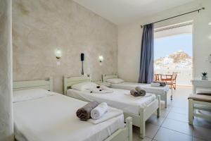 three beds in a room with a view of the ocean at Sunrise Hotel in Ios Chora