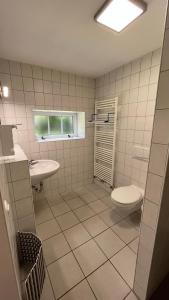 ein Bad mit einem Waschbecken, einem WC und einem Fenster in der Unterkunft Ferienhaus Alte Schule Niebüll in Niebüll