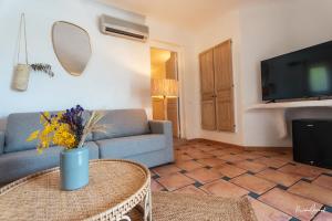 a living room with a blue couch and a tv at Hôtel Palombaggia in Porto-Vecchio