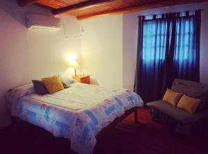 1 dormitorio con 1 cama, 1 silla y 1 ventana en La Paisanita Gualeguaychú #lapaisanitagchu en Gualeguaychú