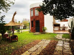 a brick house with a chair and an umbrella in a yard at La Paisanita Gualeguaychú #lapaisanitagchu in Gualeguaychú