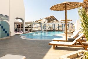 a swimming pool with chairs and an umbrella at Sunrise Hotel in Ios Chora