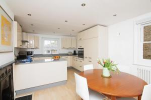 a kitchen with a wooden table and white cabinets at 2BR flat with roof terrace in London