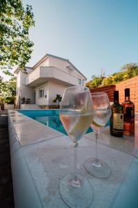 dos copas de vino sentadas en una cornisa junto a una piscina en Green & blue, en Ražanac