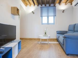 a living room with a blue couch and a tv at Aldaba Apartamentos in Toledo