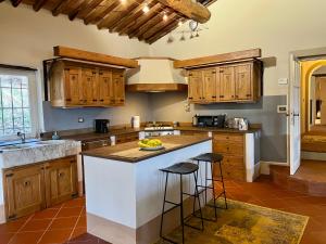 una cocina con armarios de madera y una isla con taburetes. en Servigliana, en Popiglio