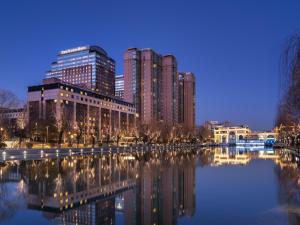 un profilo della città con edifici alti e un corpo d'acqua di Four Seasons Hotel Beijing a Pechino