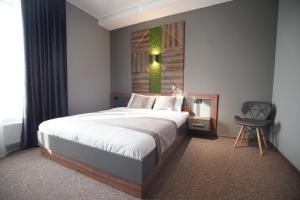 een slaapkamer met een groot bed en een stoel bij HIDE PARK HOTEL in Bokhoniki