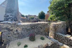 un mur en pierre avec une plante en pot dans une cour dans l'établissement Gite du belvédère à Rocamadour, à Rocamadour
