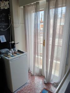 eine Küche mit weißen Vorhängen und einem Fenster in der Unterkunft Comfy Studio in Lamía