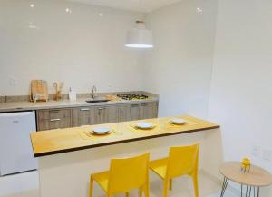 a kitchen with yellow chairs and a wooden counter top at Mar Turquesa Eco Pousada in Maragogi