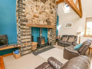 sala de estar con chimenea de piedra y muebles de cuero en Bodnant, en Tywyn
