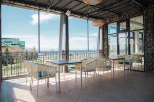 einen Balkon mit Tischen, Stühlen und Fenstern in der Unterkunft Silence hotel in Tscholponata