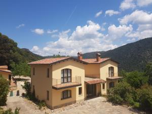 una grande casa gialla con montagne sullo sfondo di Retreat village Benessere - Il borgo dei carbonai a Esterzili