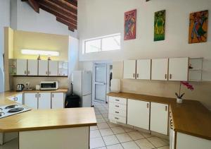 a kitchen with white cabinets and a white refrigerator at Surf and Sun Accommodation in Port Edward