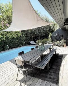 a wooden table and chairs next to a swimming pool at Luxury Villa Heleni in Herzelia 