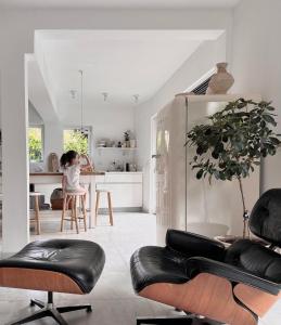 ein Wohnzimmer mit schwarzen Ledersesseln und eine Küche in der Unterkunft Luxury Villa Heleni in Herzlia