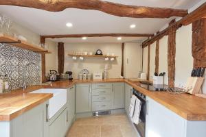 a large kitchen with white cabinets and wooden beams at Copper Cottage in Clare in Sudbury