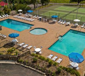 une piscine avec chaises et parasols sur un court de tennis dans l'établissement Cozy Mountain Getaway! Mountain views! 2 bed, 2 bath, Sleeps 6, à Gatlinburg