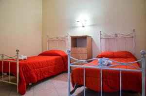 a bedroom with two beds with red sheets and a cabinet at La casa al faro in Bari